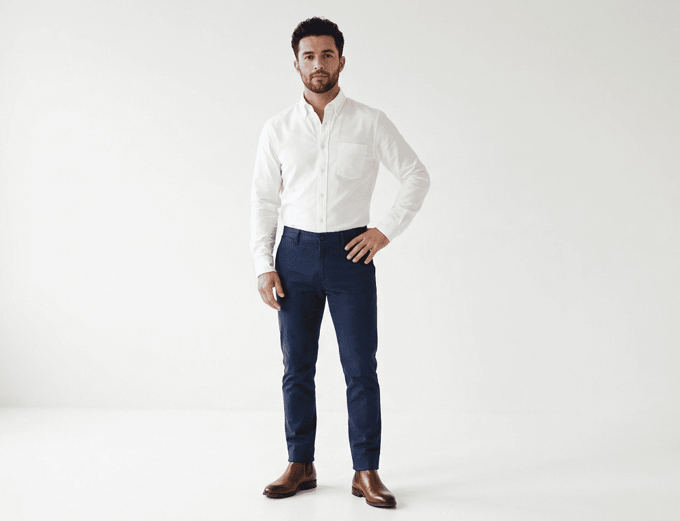 Fashion Tips for Short Men: 14 Rules That Actually Work Fashion tips for short men: full-body outfit example in slim-fit navy trousers and white Oxford shirt
